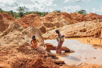 Una madre con su bebé en la espalda y su hija mayor trabajan buscando oro en una mina ilegal en Beke Route, al este de Camerún
