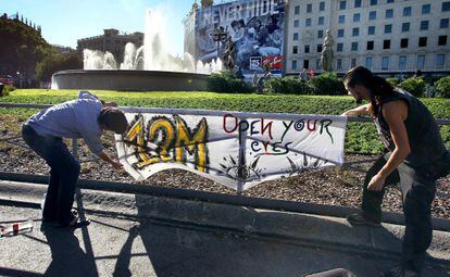 Dos simpatizantes del movimiento 15M ponen una pancarta en la plaza de Catalunya.