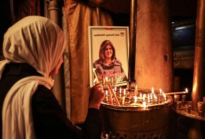 Una mujer enciende una vela frente a un póster con el retrato de Shireen Abu Akleh, en la iglesia de la Natividad en la ciudad de Belén, en Cisjordania, este miércoles.