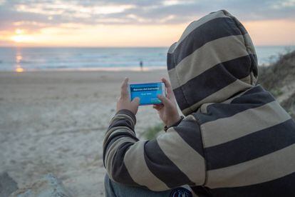 Un menor juega con su móvil a la aplicación “Narcos del Estrecho” en una de las playa de Cádiz.