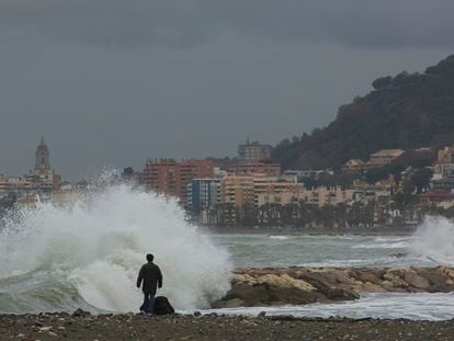 Una persona pasea este martes por la playa de Pedregalejo, en Málaga capital, cuyo paseo marítimo ha resultado afectado por el agua que ha dañado varios chiringuitos de la zona en el temporal.