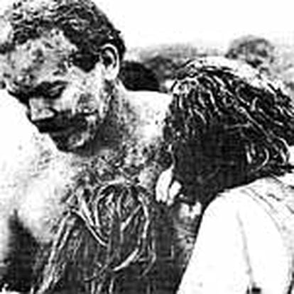 Un hombre, cubierto de fango y cenizas, consuela a su mujer y a su hija en Armero tras la inundación provocada por la erupción del volcán