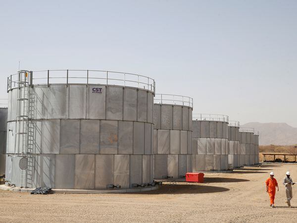 FILE PHOTO: Workers walk past storage tanks at Tullow Oil's Ngamia 8 drilling site in Lokichar, Turkana County, Kenya, February 8, 2018. REUTERS/Baz Ratner/File Photo