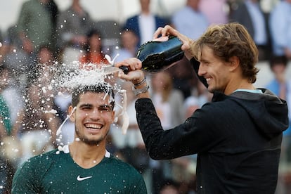 Alexander Zverev riega con champán a Carlos Alcaraz tras recibir el trofeo de ganador del Mutua Madrid Open. 