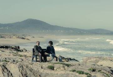 Sito Miñanco (Javier Rey), a la derecha, con Terito (Manuel Lourenzo) en la serie 'Fariña', en la playa de As Furnas, Xuño (Porto do Son).