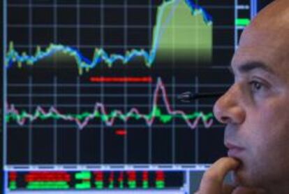 Un trader de la Bolsa de NYSE se hace el intenso con un monitor de fondo.