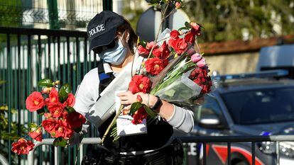 Una agente recupera flores dejadas en recuerdo de la funcionaria de policía asesinada el viernes en Rambouillet, en las afueras de París, en el último atentado terrorista en Francia