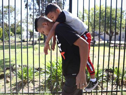 Un padre lleva a la espalda a su hijo de seis años en Oakland (California).
