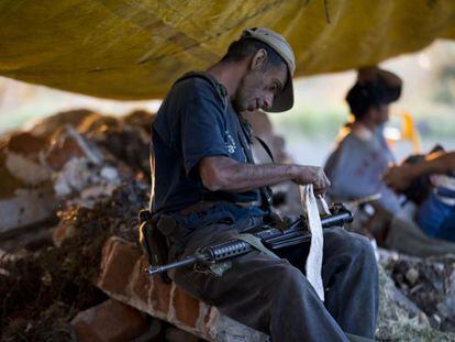 Un miembro de las autodefensas de Michoac&aacute;n limpia su arma.