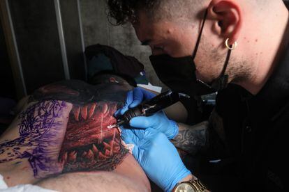Adrián Sánchez, tatuador profesional de Getafe (Madrid), con un cliente al que dibuja en la espalda a Venom, el personaje de Marvel.
