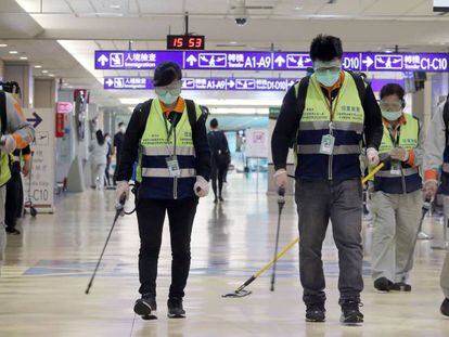 Trabajadores con mascarillas del aeropuerto internacional de Taoyuan (Taiwan, China) desinfectan las instalaciones.