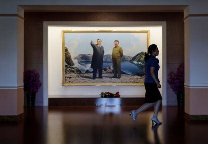 Una guía pasa junto a una imagen de los últimos líderes norcoreanos en una escuela de formación de docentes durante una visita organizada por el gobierno para periodistas extranjeros, en Pyongyang.