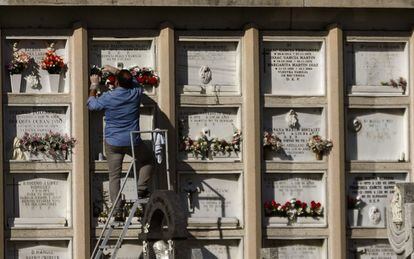 Un familiar coloca flores en un nicho del cementerio de La Almudena de Madrid.