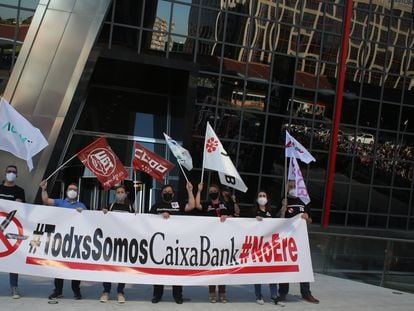 Varias personas con una pancarta en la que se lee: "Todos Somos Caixabank, no ERE", durante una concentración contra los despidos en la entidad, en las Torres Kio de Plaza de Castilla de Madrid, el 20 de mayo.