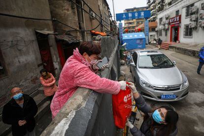 Unos vecinos de Wuhan recibían una bolsa de comida por encima de un muro, el 3 de marzo de 2020, durante el confinamiento. 