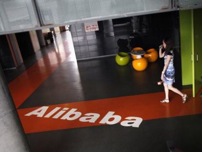 Una empleada pasa junto al logo de Alibaba en la sede de la empresa en Hangzhou (China).