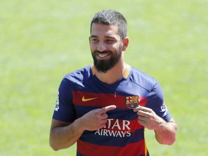 Arda Turan se&ntilde;ala su nuevo escudo en la presentaci&oacute;n.