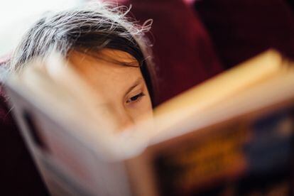 Una niña lee con atención un libro.