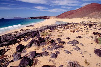 Para la portada de mi guía Vacaciones en playas con encanto se requería una imagen con dinamismo cromático. Un ámbito en el que ninguna iguala a este arenal al norte del norte canario, léase ventosa, virgen, de aguas frías y baño muy peligroso. Asombra el color blanquecino de la arena y, a dos kilómetros, la isla volcánica de Montaña Clara.