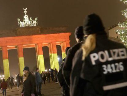 Policías alemanes patrullan en torno a la Puerta de Brandemburgo, en el centro de Berlín, iluminada con los colores de la bandera alemana.