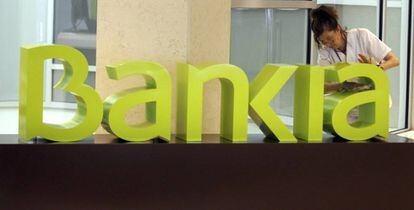 Una operaria limpia el logo de Bankia. 