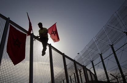 Un activista retira una pancarta y una bandera marroquí de las alambradas de la frontera de Melilla.