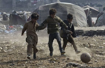 Niños paquistaníes juegan a fútbol en un barrio chabolista de Lahore.