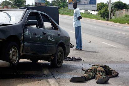 Un hombre observa el cadáver de un miliciano, leal a Laurent Gbagbo, en una calle de Abiyán.