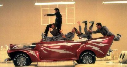 ¿Cuántos coches conoces que tengan su propia canción? En 'Grease' (1978), los chicos sólo suspiraban por una cosa que no tuviera pechos: el bólido definitivo. En una de sus escenas más memorables, mientras tuneaban su Ford DeLuxe de 1948, la panda de Danny Zuko (John Travolta) compartía la fantástica ensoñación de convertir aquel carro en el coche de sus anhelos: el 'Greased Lightning' ['Rayo Engominado', aunque suene ridículo]. Así que ese modelo aparece dos veces: en una versión más terrenal (blanco y gris), con la que corrían por aquí y por allá, y en su formato quimérico: rojo fresa, con unas alas más o menos apañadas en la parte trasera y con sus relámpagos blancos en los laterales. Al final de la película termina el curso en el instituto, Travolta se redime, se compromete con Olivia Newton-John y no se sabe por qué, seguramente por la magia del cine, reaparece el Ford DeLuxe soñado (el rojo) y se los lleva volando como si nada.

DÓNDE ESTÁ AHORA ESE BÓLIDO. El 'Greased Lightning' fue adquirido por el Volo Auto Museum (Illinois, EE UU), y allí se exhibe actualmente junto con otros colegas famosos: KITT ('El coche fantástico'), la ambulancia de los Cazafantasmas, el Bluesmóvil de los Blues Brothers o la moto del Motorista Fantasma, por ejemplo.