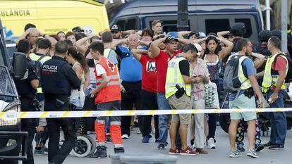 Un grupo de gente con los brazos en alto ante el despliegue policial en las Ramblas de Barcelona. 