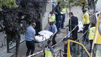 Empleados de la funeraria trasladan el cuerpo de unas las víctimas del triple crimen de Usera.