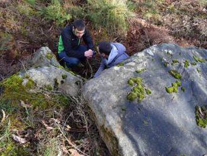 Dos miembros de MariñaPatrimonio, junto a las piedras de la mámoa que están a la luz.