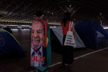Dos seguidores de Lula da Silva en el campamento en Parque da Cidade. Uno de ellos está envuelto en una bandera con la imagen del futuro presidente. 