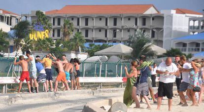 Bañistas agarrados este jueves a la valla del aeropuerto Princesa Juliana, en Sint Maarten, para ver el despegue y aterrizaje de los aviones.