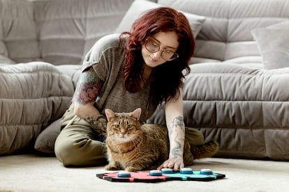 A woman teaching her cat to speak with one of FluentPet's tablets.