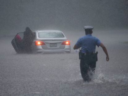 Un policía de Filadelfia acude a ayudar a una persona atascada en su coche en medio de una inundiaciíon producto del huracán Isaias.