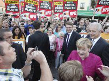 La canciller alemana Angela Merkel (2&ordm;dcha)saluda a sus simpatizantes junto al presidente de Sajonia, Stanislaw Tillich (dcha), durante una campa&ntilde;a electoral en Oschatz (Alemania).