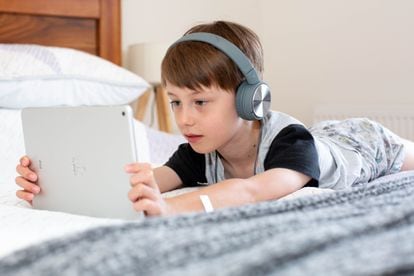 Un niño usa una tablet en su dormitorio.