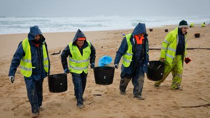 Operarios retiran pellets en una playa del Parque Natural de Corrubedo, en A Coruña, este martes.