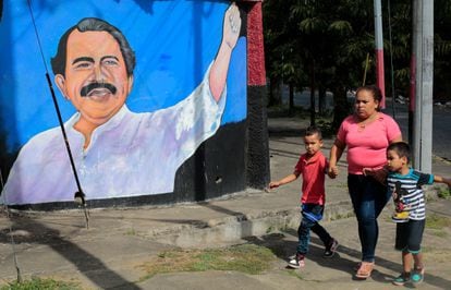 A woman walks with her children in front of a mural by Daniel Ortega this Monday in Managua.