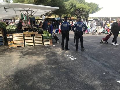 Dos policías municipales delante de un puesto vacío en el mercadillo de Entrevías, este domingo.