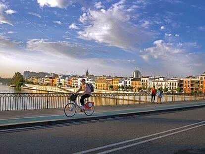 Una joven cruza el puente de Isabel II en una de las bicicletas del servicio público. El abono anual, disponible para residentes, cuesta 33,33 euros; el semanal, 13,33.