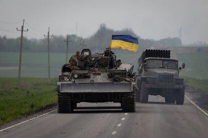 Un carro con una bandera de Ucraina junto a un camion lanzacohetes circulan por una carretera cercana a Lissitxansk.