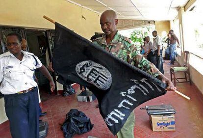 Un polic&iacute;a keniano sostiene una bandera isl&aacute;mista incautada en las recientes redadas en mesquitas en Mombasa.