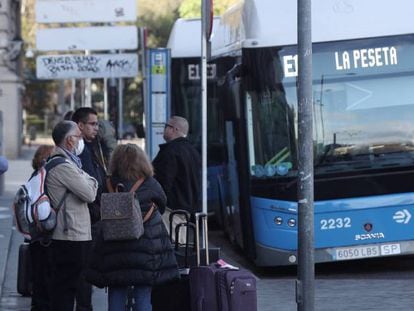 Varias personas esperan el autobús en una parada de la EMT en Cibeles, en Madrid. 