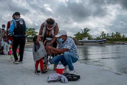 Dos adultos preparan a una niña para un viaje en una embarcación, en Necoclí (Colombia), en agosto de 2021.
