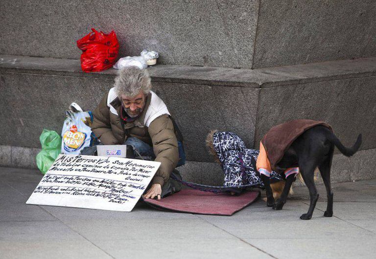 Una persona sin hogar con dos perros, en una calle de Madrid.