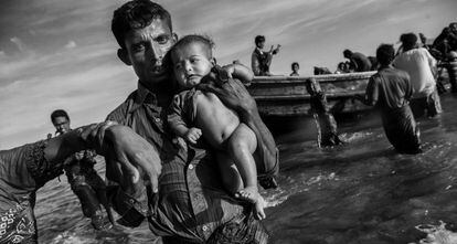 Un refugiado rohingya lleva en sus brazos a un bebé después de llegar en barco a Bangladesh después de huir de su pueblo en Myanmar, el 1 de octubre de 2017 en Cox's Bazar, Bangladesh.
