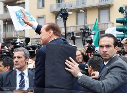 Un grupo de guardaespaldas cubre al primer ministro italiano, Silvio Berlusconi, a su salida del Palacio de Justicia de Milán.
