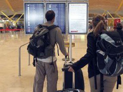 Unos viajeros consultan vuelos de salida en uno de los paneles de la T-4 del aeropuerto de Barajas de Madrid.